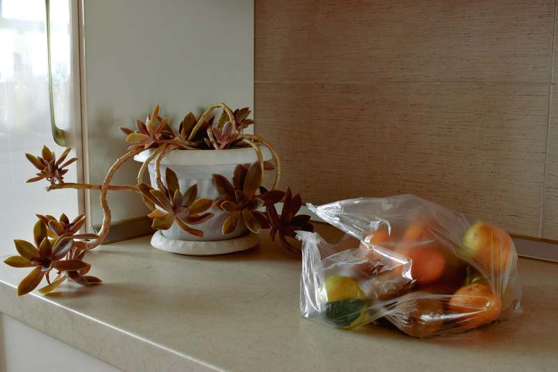 Close-up of colorful silicone food storage bags holding chopped vegetables and grains on a marble countertop